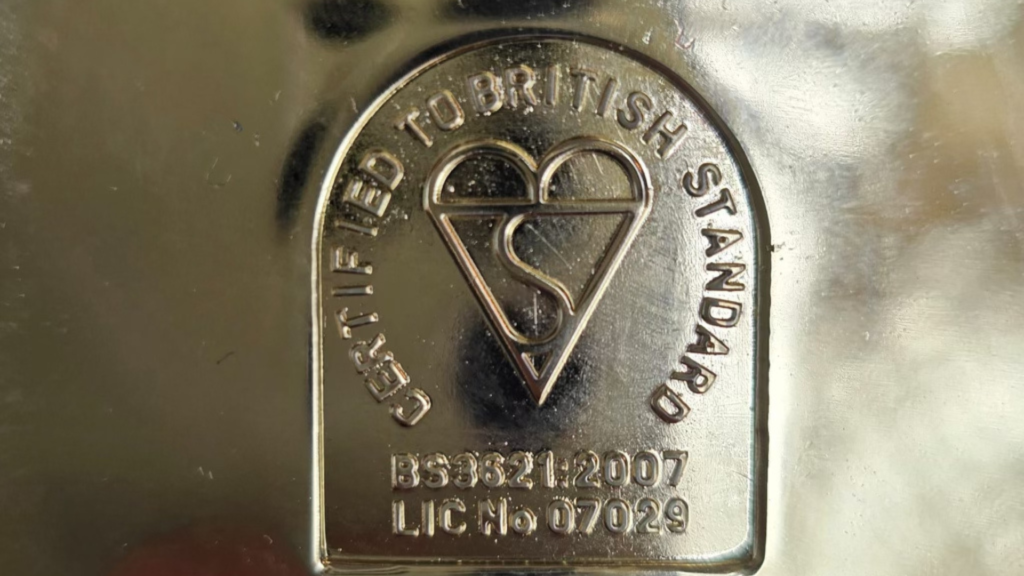 British standard 3621 on a yellowish steel door lock.