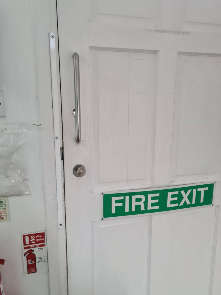White door with a green label "fire exit" | Locksmithw12